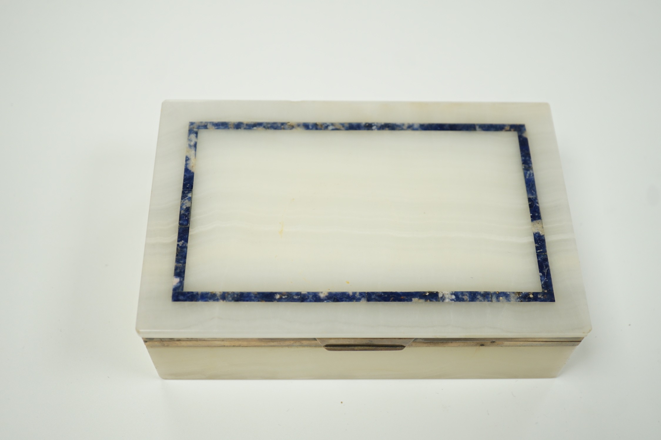 A George V silver mounted, lapis lazuli banded white onyx rectangular cigarette box, George Betjemann & Sons, London, 1919, 15.3cm.